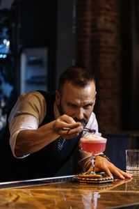 Portrait of young man with drink on table