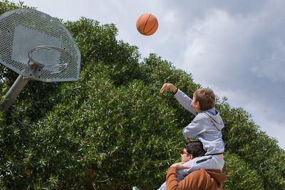 Man playing with ball and plants against sky