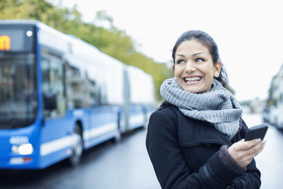 Smiling mid adult woman talking on smart phone on street