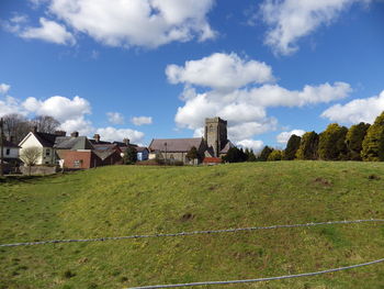 Houses on grassy field against cloudy sky