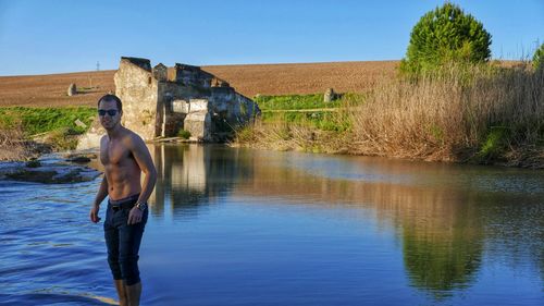 Man standing by lake against sky