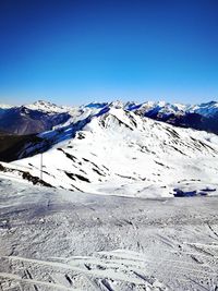 Scenic view of snowcapped mountains against clear blue sky