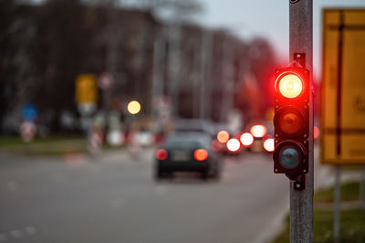 A city crossing with a semaphore on blurred background with cars in the evening streets, red light