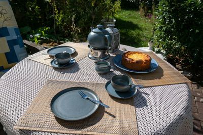 The table on the terrace is set. the blue tea set, plates, cups and the delicious cake.it is a warm, 