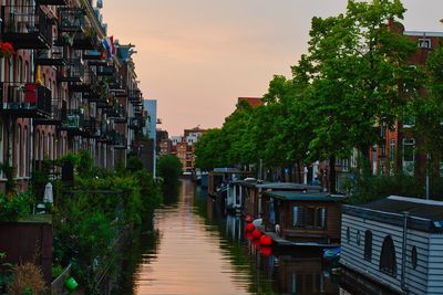 Canal amidst buildings against sky during sunset
