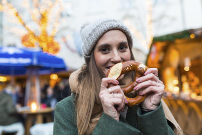 Portrait of smiling young woman with pretzel at christmas market