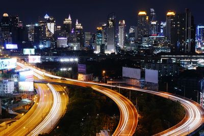 High angle view of light trails on road amidst buildings in city at night