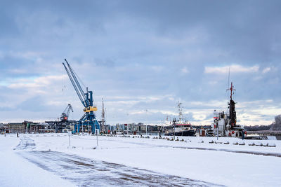 Cranes on snow covered city against sky