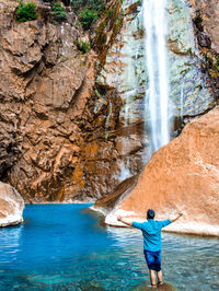 Rear view of man standing by waterfall