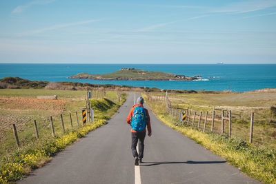 Rear view of woman walking on road against sky