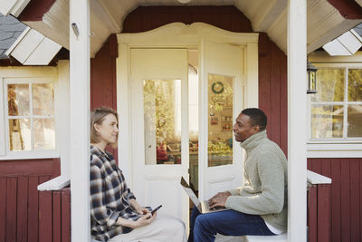 Couple sitting in front of wooden house