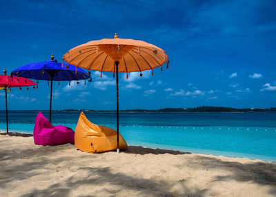 Umbrellas on beach against blue sky