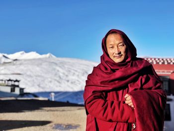 Portrait of monk standing against snowcapped mountain
