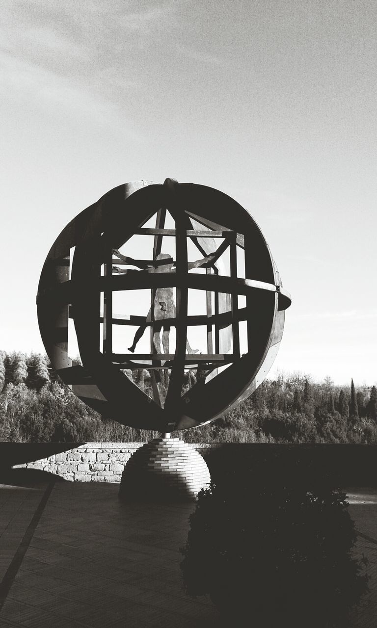 sky, built structure, circle, tree, metal, architecture, tranquility, no people, day, outdoors, nature, tranquil scene, cloud - sky, metallic, sunlight, geometric shape, absence, cloud, shadow, wheel