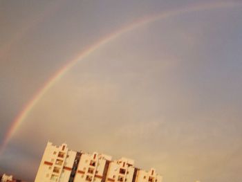Low angle view of rainbow over building against sky