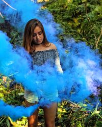 Young woman standing by smoke against plants