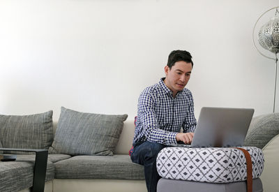 Man using mobile phone while sitting on sofa