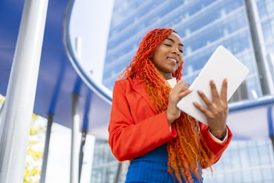 Smiling businesswoman using tablet pc in office park