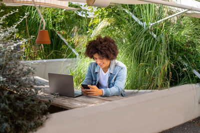 Young woman using laptop while sitting on field