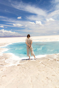 Rear view of woman standing at beach against sky