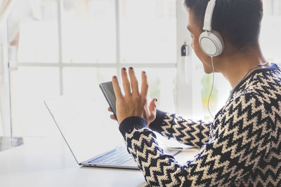 Midsection of man using mobile phone while sitting on table