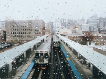 High angle view of trains at railroad station seen through glass window during rainy season