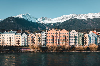 Buildings by mountains against clear sky during winter