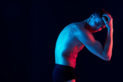 Side view of young man against black background