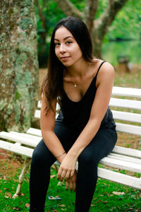 Portrait of smiling young woman sitting on bench