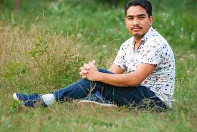 Portrait of young man sitting on field