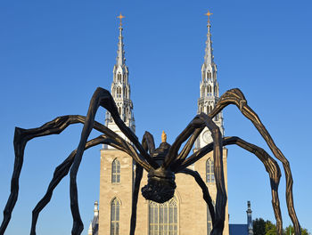 Low angle view of sculpture on building against blue sky