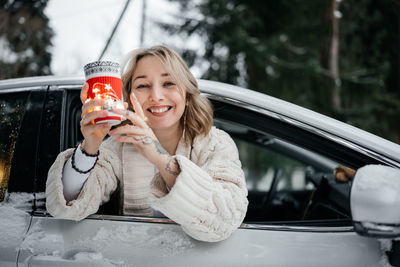 Portrait of young woman holding car