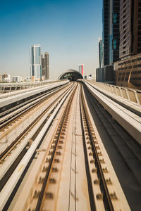 Railroad tracks in city against sky