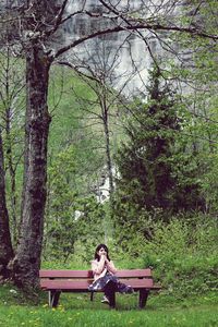 Woman sitting on tree in park