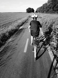 Rear view of boy riding bicycle on road