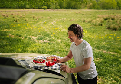 Side view of man standing by car and eating easter food