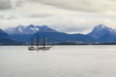 Sailboat on snowcapped mountains against sky
