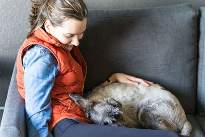 Girl is staying at home with a pup on the couch