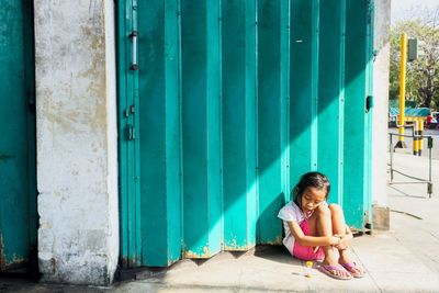 Full length of young woman sitting on door