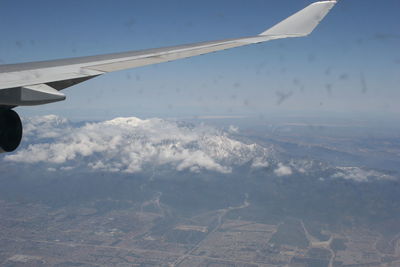 Aerial view of airplane wing over landscape against sky