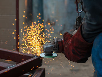 Cropped image of worker using machinery on metal at workshop