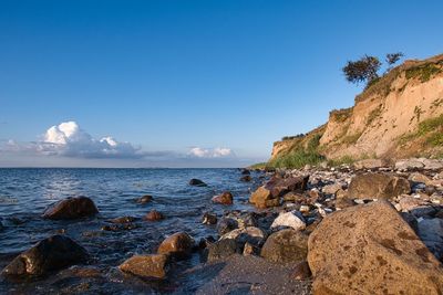 Rocks on beach against blue sky