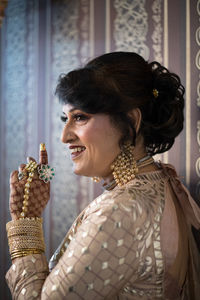 Smiling woman wearing traditional clothing standing against wall