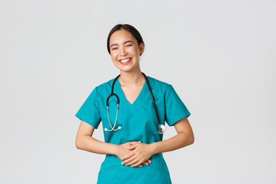 Smiling young woman standing against white background