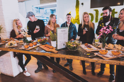 Friends standing by food at table in restaurant