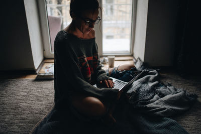 Woman using laptop near window at home