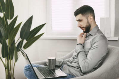 A handsome young man of oriental appearance works at home with a laptop. doing homework online