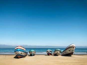 Deck chairs on beach against clear blue sky