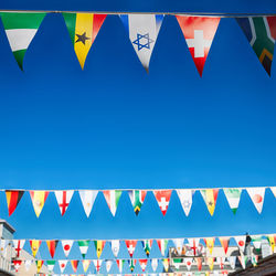 Low angle view of flags against clear blue sky