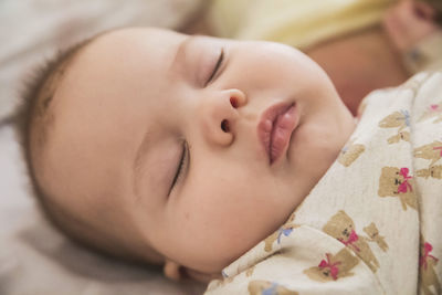 Close-up of cute baby boy lying on bed at home